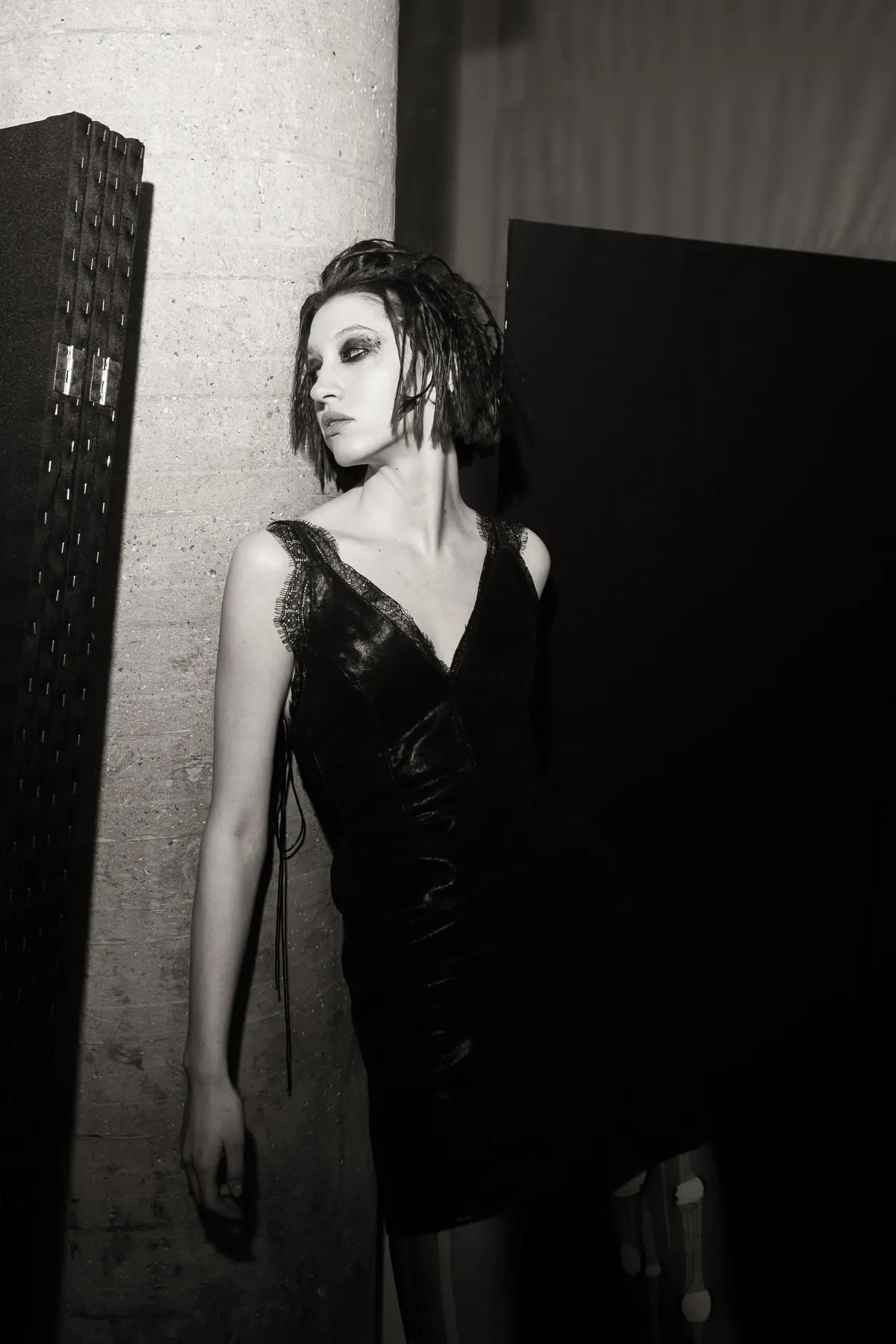 Black and white: a model in a laced leather dress beside a bare concrete column